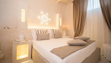 Hotelkamer met een groot bed, nachtlampjes, decoratieve wandverlichting en uitzicht op het buitenleven door gordijnen.