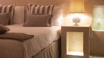 A bedroom with a bed, pillows, a bedside lamp, and a nightstand with a bottle.