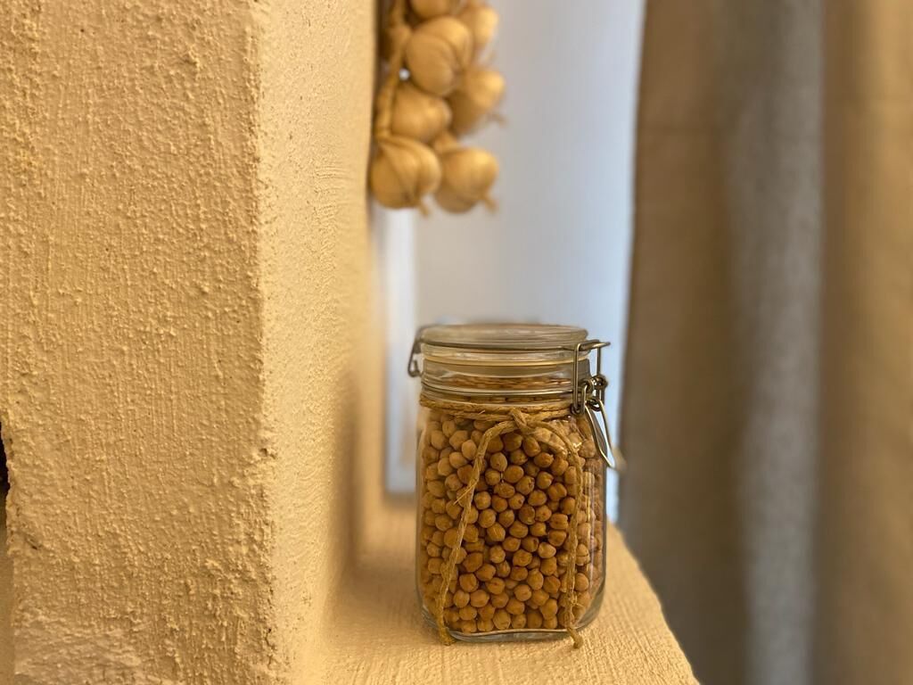 Un bocal en verre rempli de petits objets ronds, ficelés ensemble et posé sur une étagère en bois.
