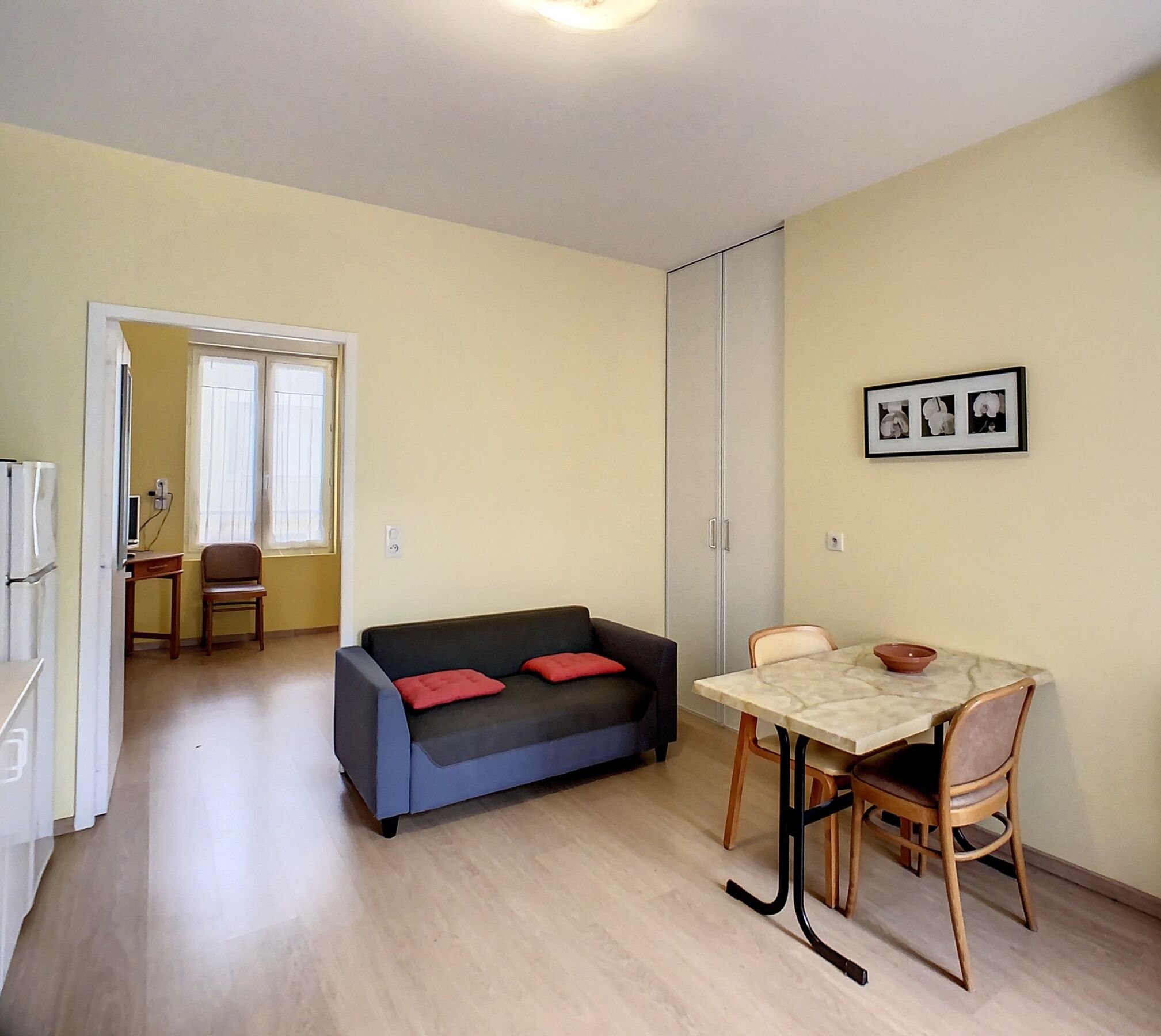 Un espace de vie compact comprenant un canapé, une table à manger et un coin cuisine.