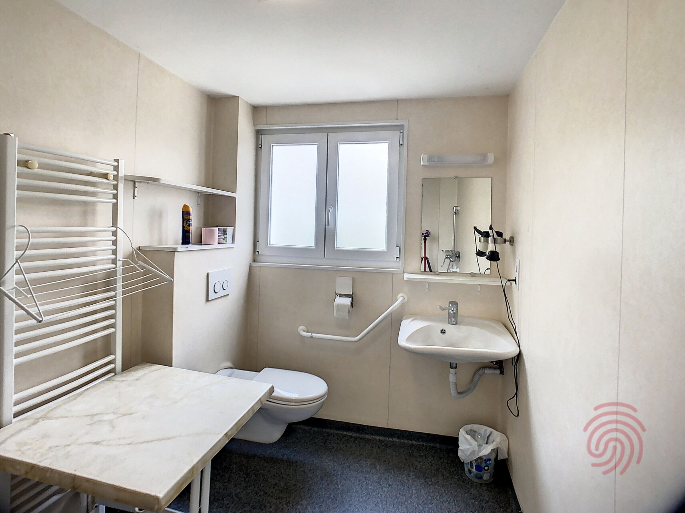 Ein kleines Badezimmer mit Toilette, Waschbecken und Handtuchhalter.