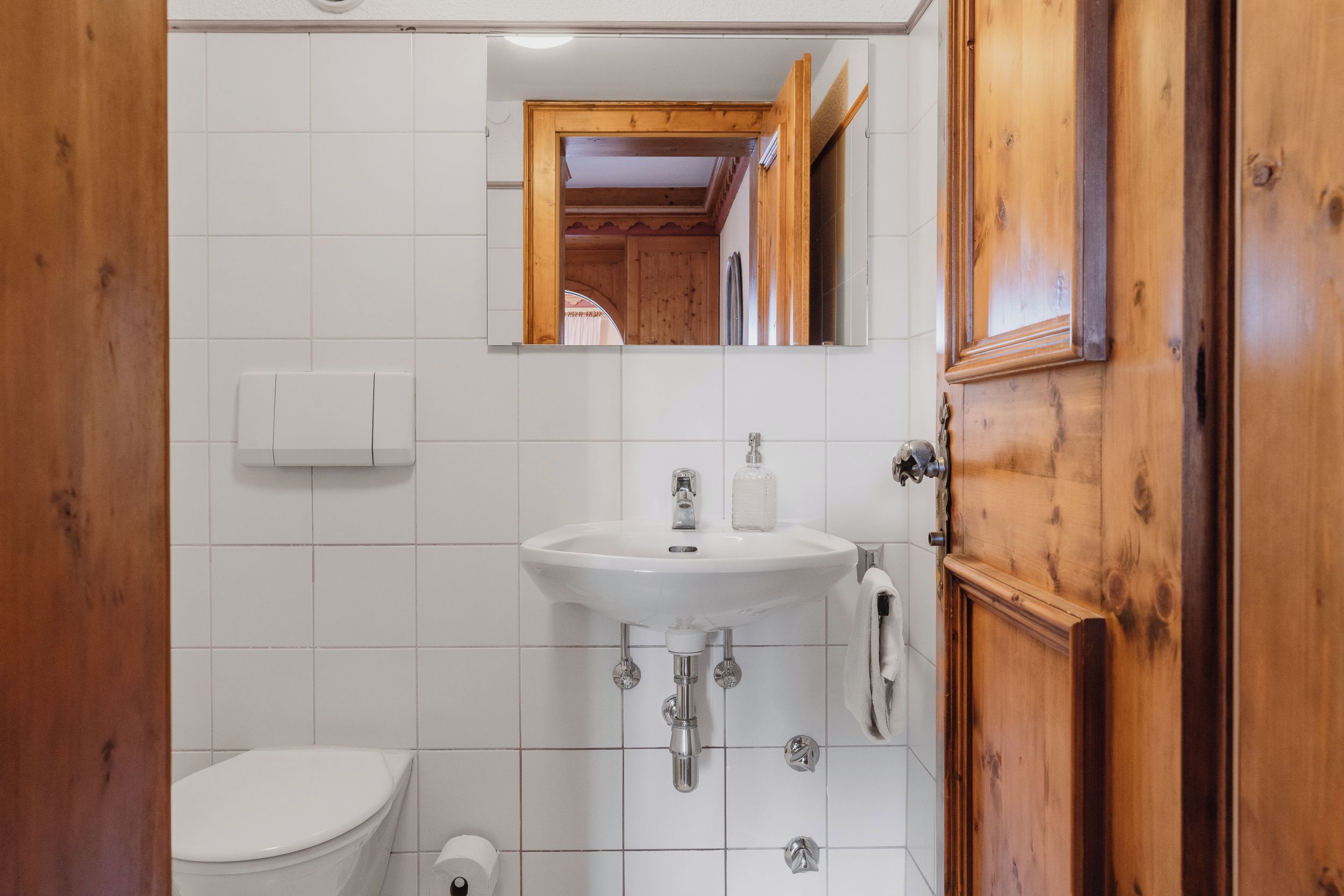 A bathroom with a white sink, a mirror, and a wooden door.