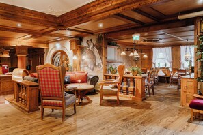 Una habitación acogedora con paneles de madera, chimenea, un mural y un comedor con muebles de madera.