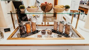 A display of food items including fruits, nuts, and grains, with labels indicating their names and prices. - Hotel Schwarzer Adler (Tannheim)