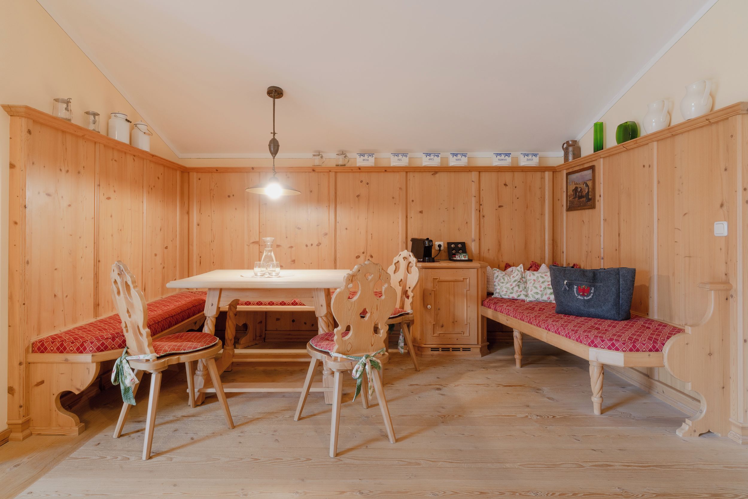 A wooden room with a dining table, chairs, a bench, and a cabinet.