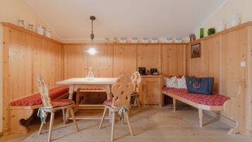 A wooden room with a dining table, chairs, a bench, and a cabinet.