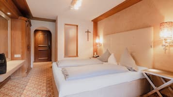 Ein Hotelzimmer mit Doppelbett, Nachttisch, Wandlampe und einem Kreuz an der Wand.