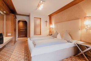 Habitación de hotel con cama doble, mesita de noche, lámpara de pared y una cruz en la pared.