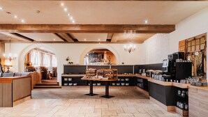 A café with a wooden interior, a buffet counter, and a seating area with tables and chairs. - Hotel Schwarzer Adler (Tannheim)