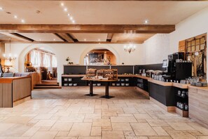 A café with a wooden interior, a buffet counter, and a seating area with tables and chairs. - Hotel Schwarzer Adler (Tannheim)