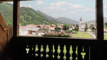 Vista da janela com vista para uma vila, uma igreja e montanhas ao fundo.