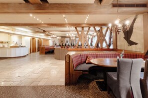 Interior de restaurante con vigas de madera, una zona de estar central con una mesa redonda y un mostrador con barra libre.