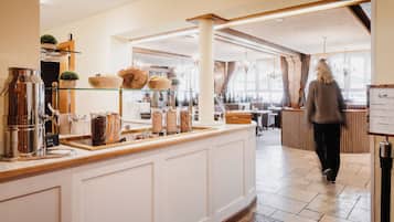 Ein Café mit einer Holztresen, Regalen mit Schalen und Gläsern sowie einer Speisekarte.