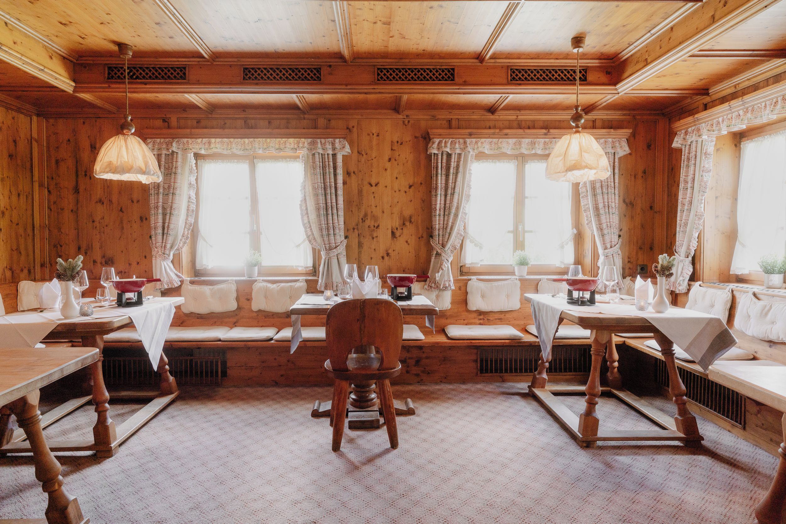 Een houten interieur met een zithoek, tafels en hangende lampen.