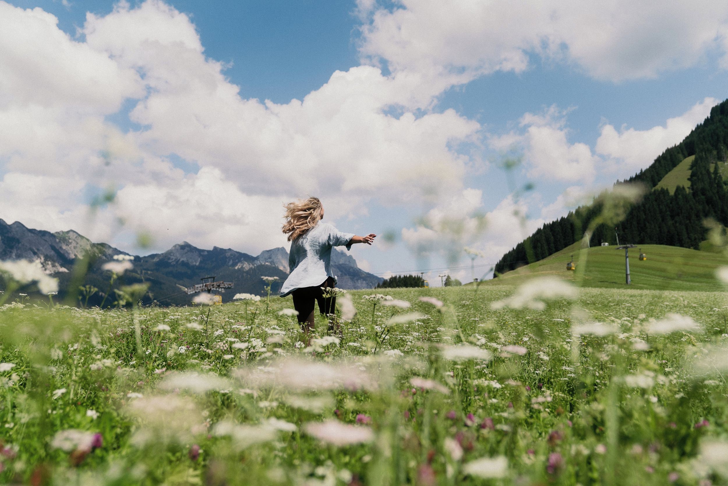 Eine Person steht in einem Feld mit Bergen im Hintergrund.