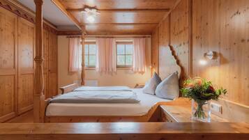 Una habitación de madera con una cama, una mesa y un florero con flores.