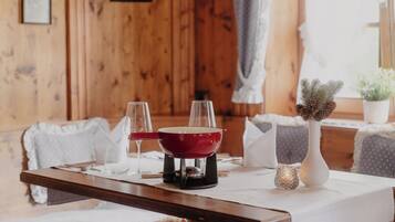 A dining table with a red pot, two glasses, and a candle.