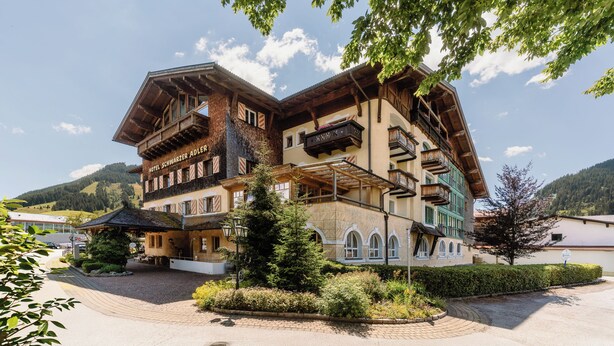 A traditional chalet-style hotel with multiple balconies and a mountain backdrop. - Hotel Schwarzer Adler (Tannheim)