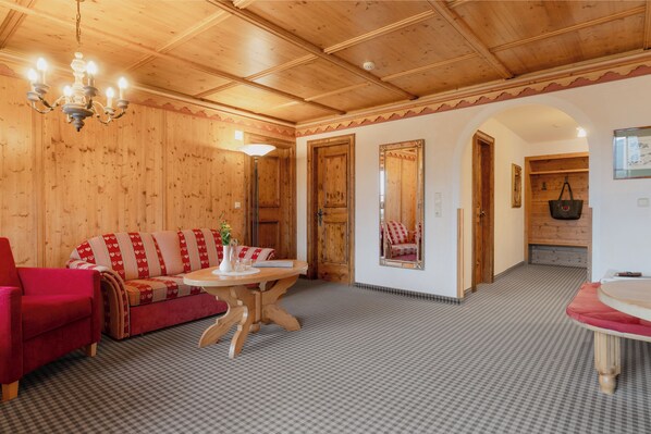 Un interior de madera con un sofá rojo, una mesa con un jarrón y una araña.