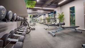 Uma academia com diversos equipamentos de musculação, esteiras e aparelhos de exercício.