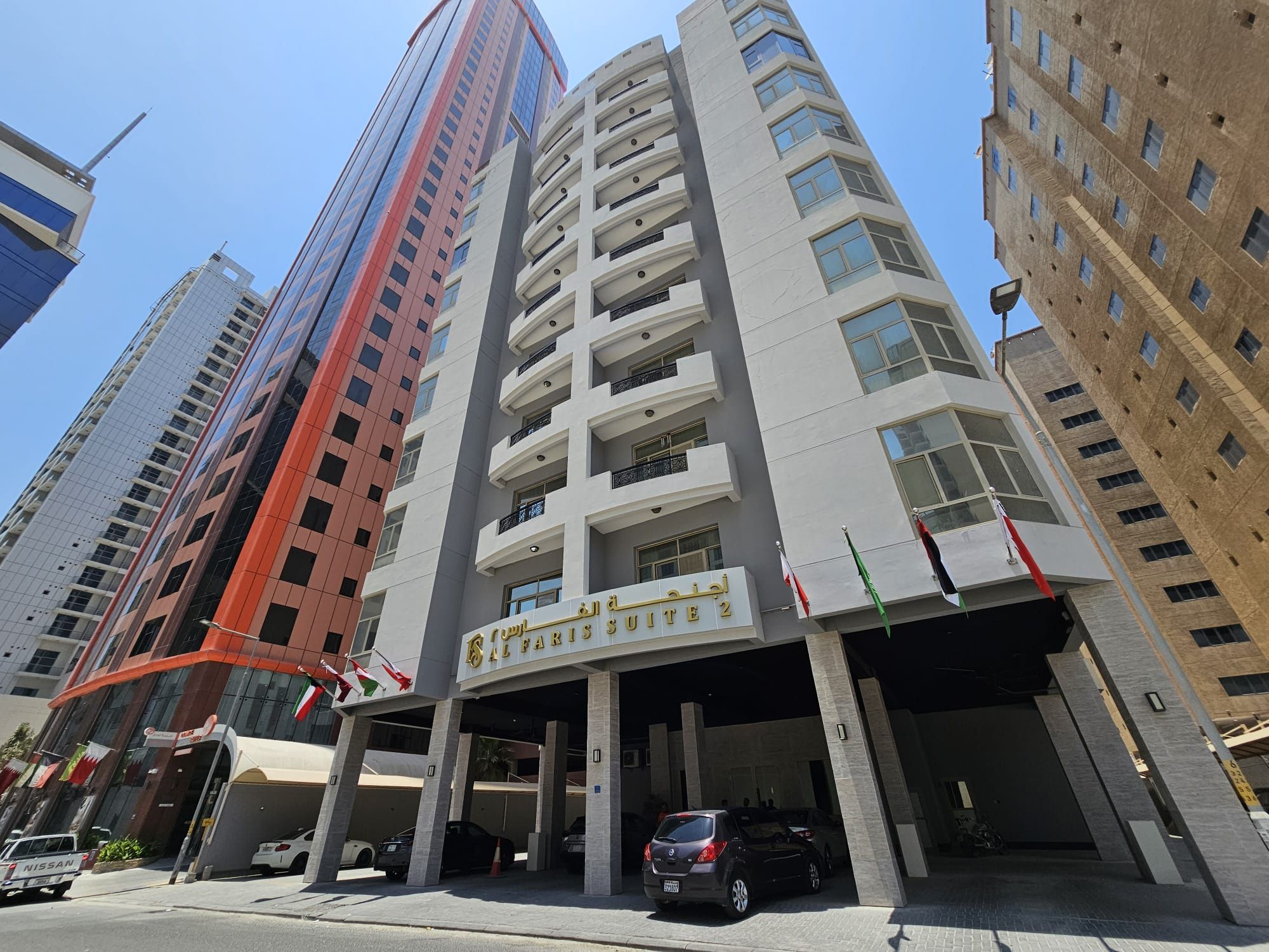 Un hôtel à plusieurs étages, doté d’une entrée imposante, d’un parking souterrain et de plusieurs drapeaux.