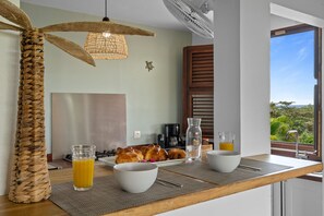 Un plateau de petit-déjeuner avec des croissants, du café et du jus, disposé sur une table offrant une vue sur la verdure environnante.