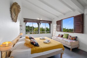 Une chambre à coucher avec un lit, un canapé, une fenêtre et une lampe.