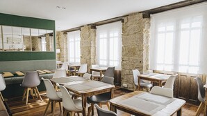 A restaurant with wooden tables and chairs, stone walls, and large windows. - Hotel Casona del Nansa (Herrerias)