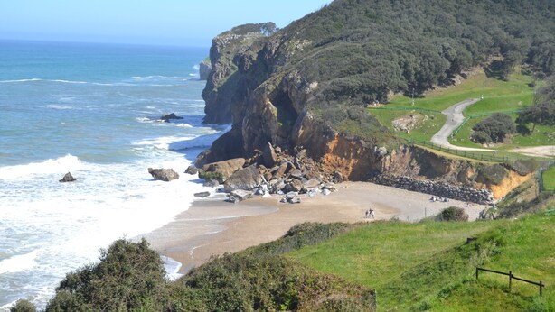 A coastal landscape with a beach, rocky cliffs, and a winding road. - Hotel Casona del Nansa (Herrerias)