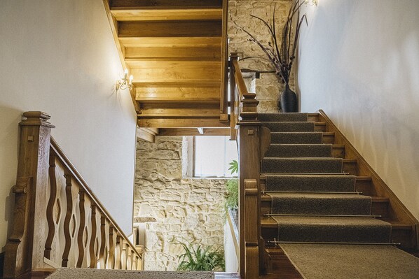 Una escalera de madera con peldaños alfombrados que conduce a un muro de piedra y una ventana.
