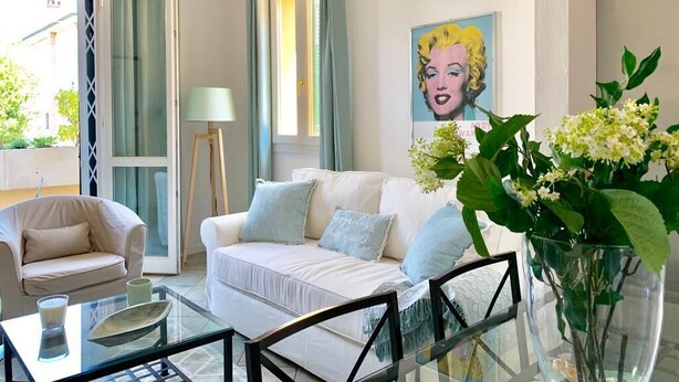 Un salon avec un canapé blanc, une table basse en verre et un tableau accroché au mur.