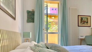 Une chambre à coucher avec un lit, une fenêtre avec des rideaux, un bureau et une chaise.