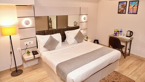 Ein modernes Hotelzimmer mit einem großen Bett, Nachttischen, einem Schreibtisch und einem Spiegel.