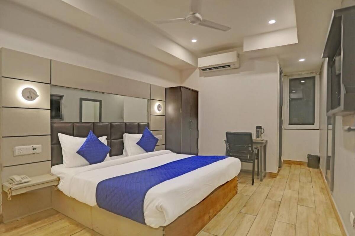 Una habitación de hotel con cama, mesita de noche y ventilador de techo.