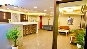 Eine moderne Hotelhalle mit Empfangstresen, Sitzgelegenheiten und Topfpflanzen.