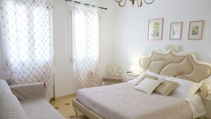 A neatly arranged bedroom with a large bed, bedside tables, and a chair.