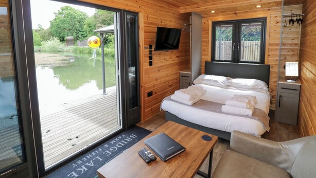 Ein modernes Holzhaus mit einem großen Bett, einem Fernseher und Seeblick.