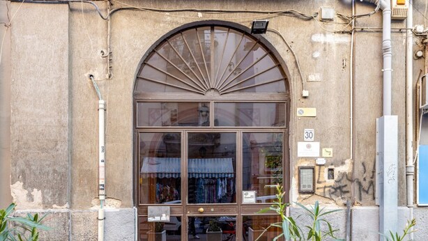 Una vetrina con un'ampia finestra ad arco, un cartello che indica un limite di velocità di 30 e una piccola tenda da sole.