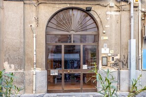 Une devanture de magasin avec une grande fenêtre en arc de cercle, un panneau indiquant une limitation de vitesse à 30, et un petit auvent.