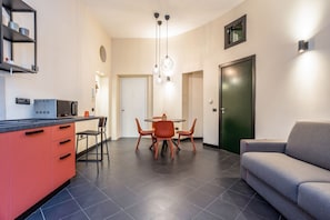 A modern kitchen with a dining area, a sofa, and a door.