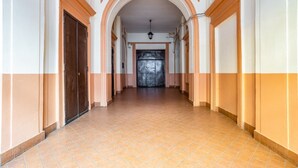 Un corridoio con pavimento piastrellato, porte ad arco e una lampada a sospensione.