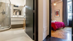 Una camera d'albergo con doccia, un letto, un comodino e una finestra.