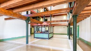 Un interior espacioso con altos vigas de madera, un quiosco central y suelo de baldosas.