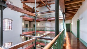 Un interior con varios niveles, vigas de madera, balcones y un pasillo.