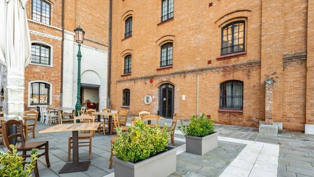 A courtyard with outdoor seating, brick buildings, and planters.