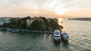 A river with boats docked, a bridge, and buildings in the background. - GuestHost - Molino Stucky Residence Galea Suite (Venezia)