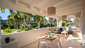 A sunlit balcony with a dining table, chairs, and a sofa. - Family Dominicus Apartment - Bayahibe (Bayahibe)