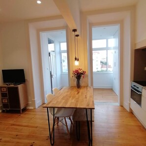 Uma cozinha moderna com forno embutido e uma sala de jantar com mesa e cadeiras de madeira.