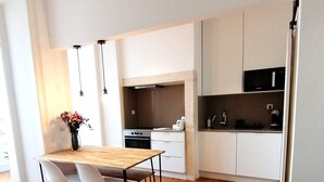 A modern kitchen with white cabinets, a wooden dining table, and two chairs. - T2 w/ balcony (Lisboa)