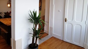 A hallway with a wooden floor, a potted plant, and a white door. - T2 w/ balcony (Lisboa)